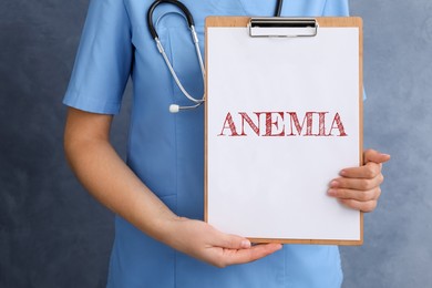 Image of Doctor holding clipboard with word ANEMIA on blue background, closeup