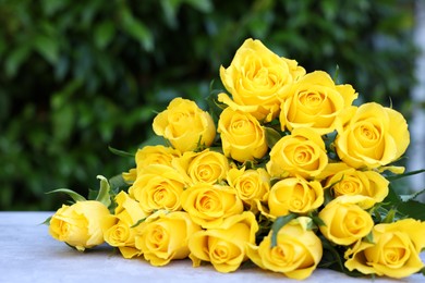 Beautiful bouquet of yellow roses on light table outdoors, closeup