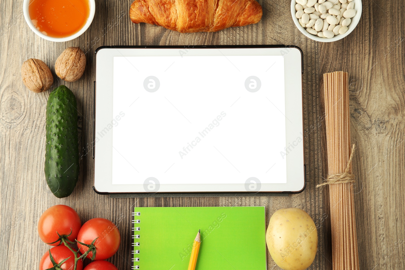 Photo of Glycemic index. Tablet with blank screen, different products and notebook on wooden table, flat lay