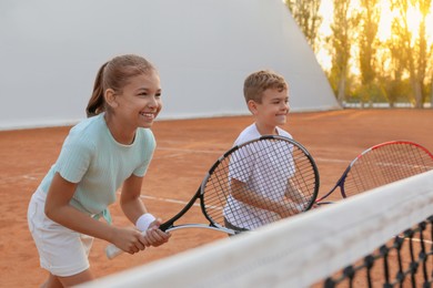 Photo of Happy children playing tennis on court outdoors