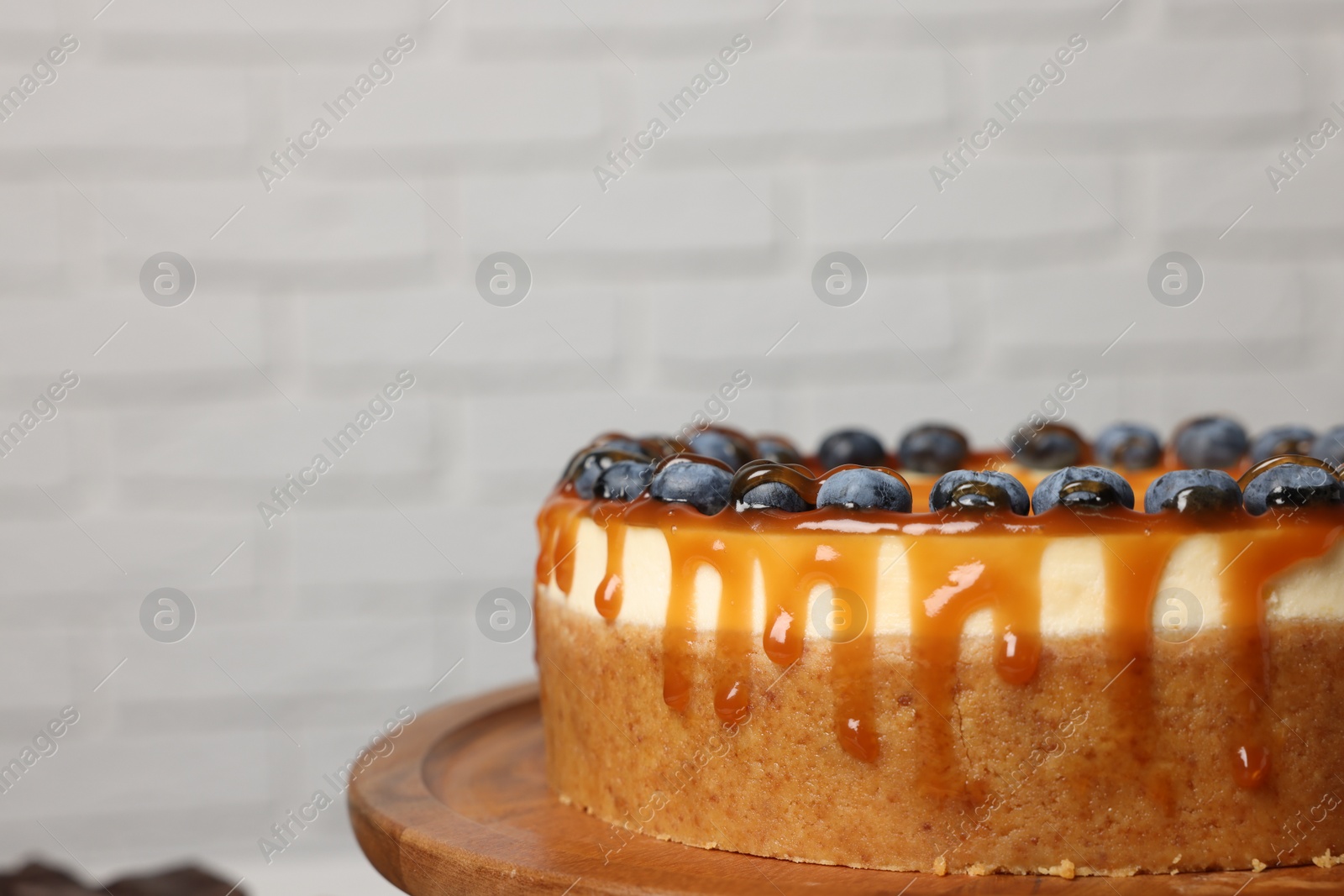 Photo of Delicious cheesecake with caramel and blueberries, closeup. Space for text