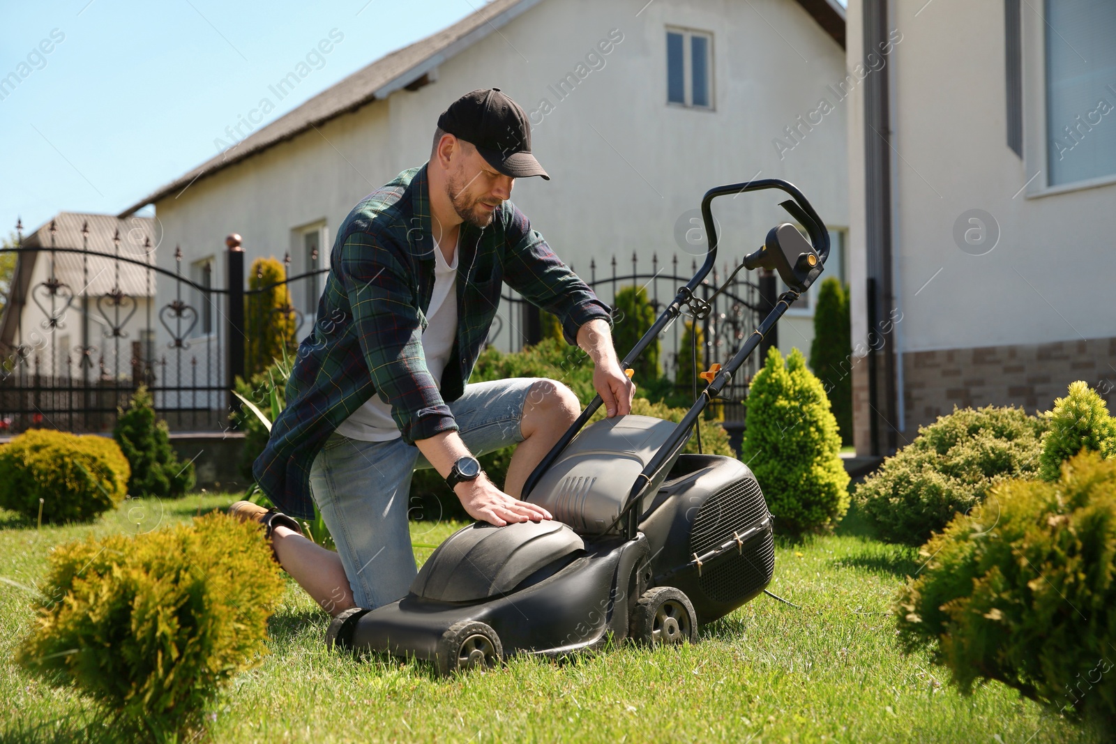 Photo of Man cutting green grass with lawn mower in garden