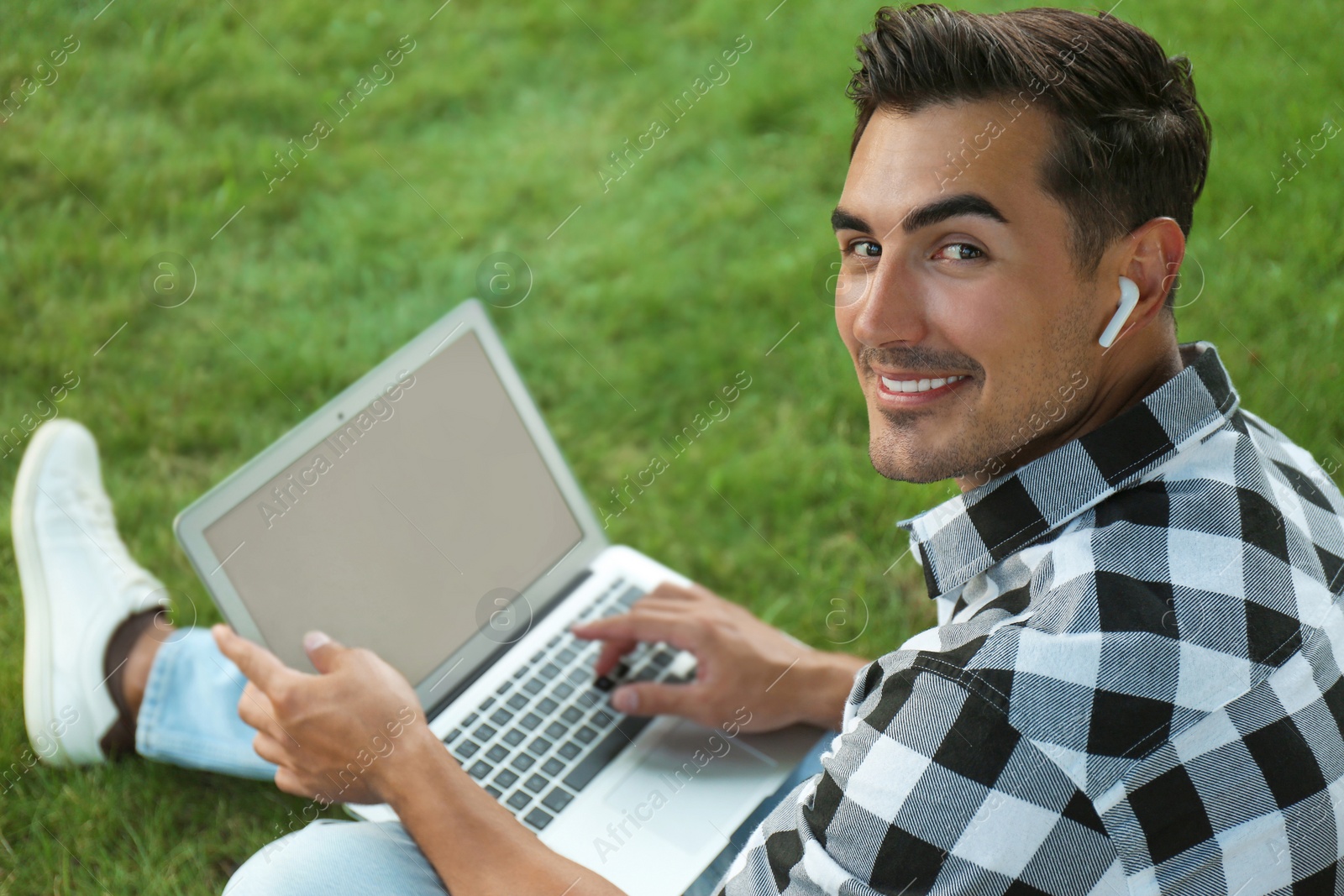 Photo of Portrait of young man with laptop outdoors. Space for design