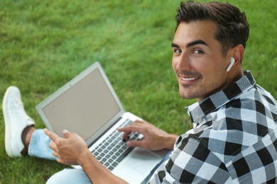 Portrait of young man with laptop outdoors. Space for design