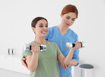 Professional physiotherapist working with female patient in rehabilitation center