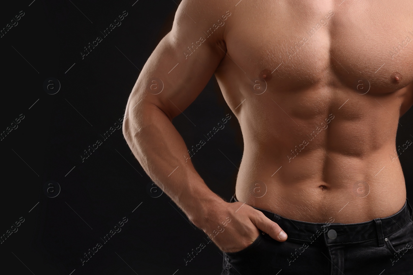 Photo of Muscular man showing abs on black background, closeup and space for text. Sexy body