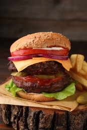 Photo of Tasty cheeseburger with patties and French fries on tree stump, closeup