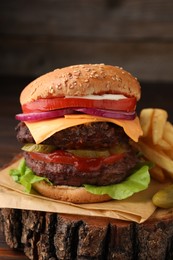 Tasty cheeseburger with patties and French fries on tree stump, closeup