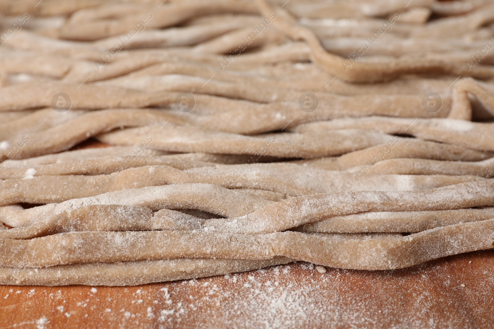 Photo of Uncooked homemade soba (buckwheat noodles) on wooden table, closeup