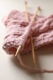 Photo of Pink knitting and needles on beige background, closeup