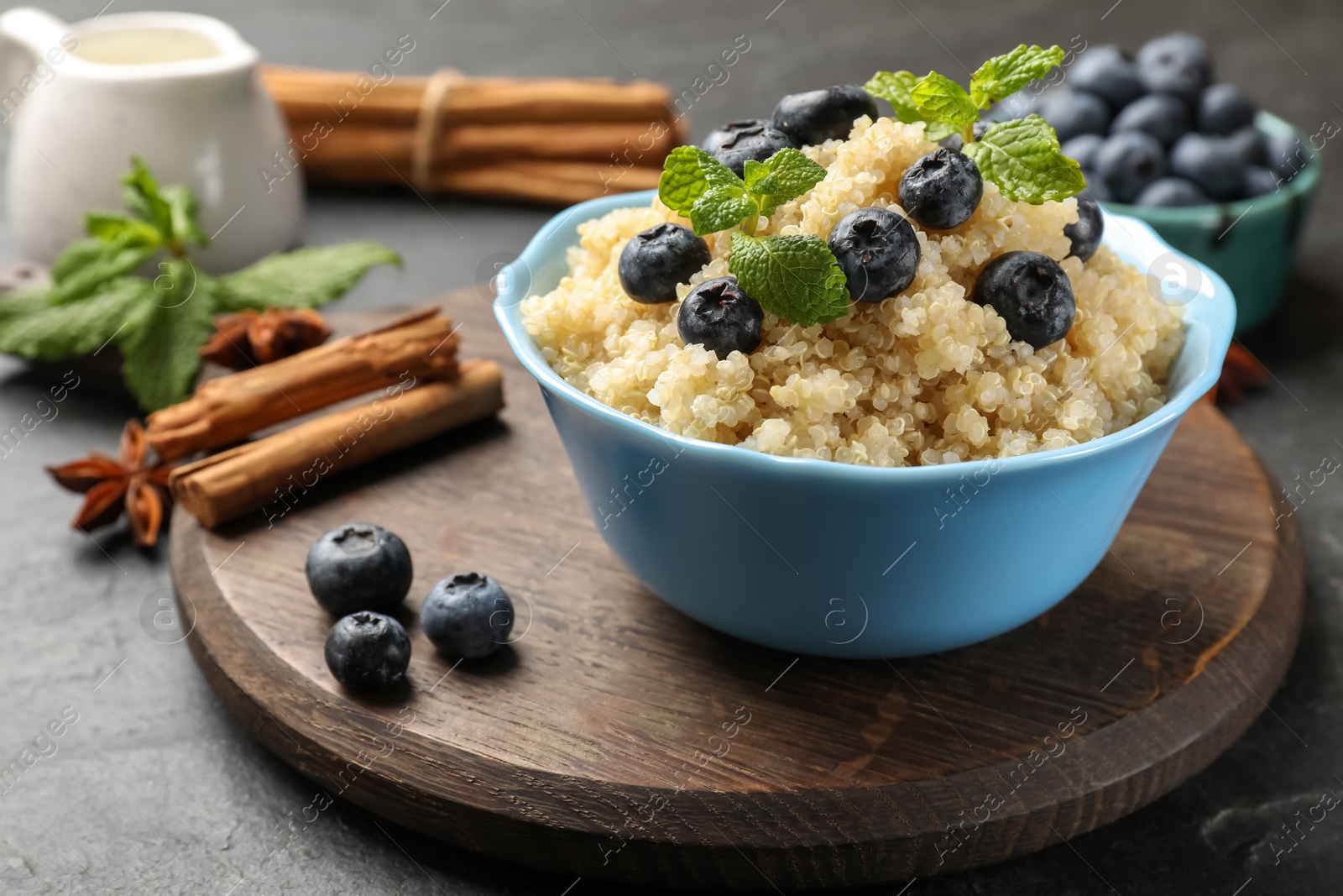 Photo of Tasty quinoa porridge with blueberries and mint in bowl on table