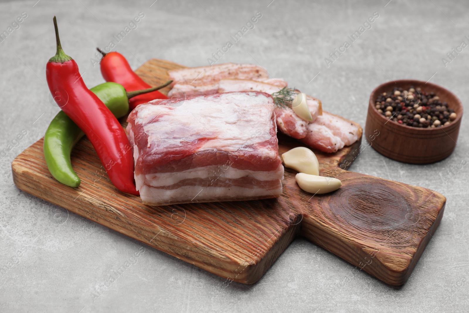 Photo of Tasty pork fatback with spices on grey table, closeup