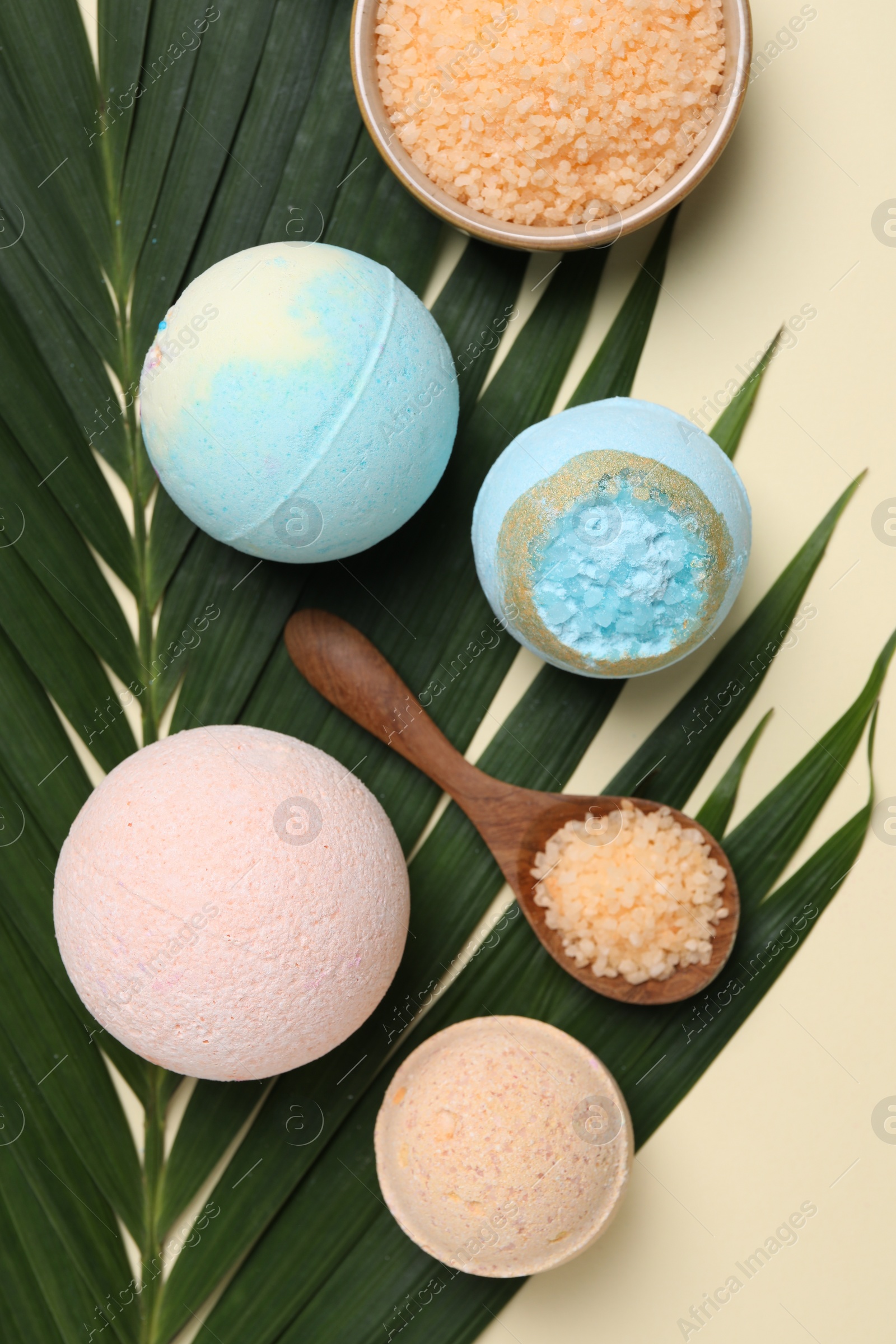 Photo of Bath bombs, green leaf and sea salt on beige background, flat lay