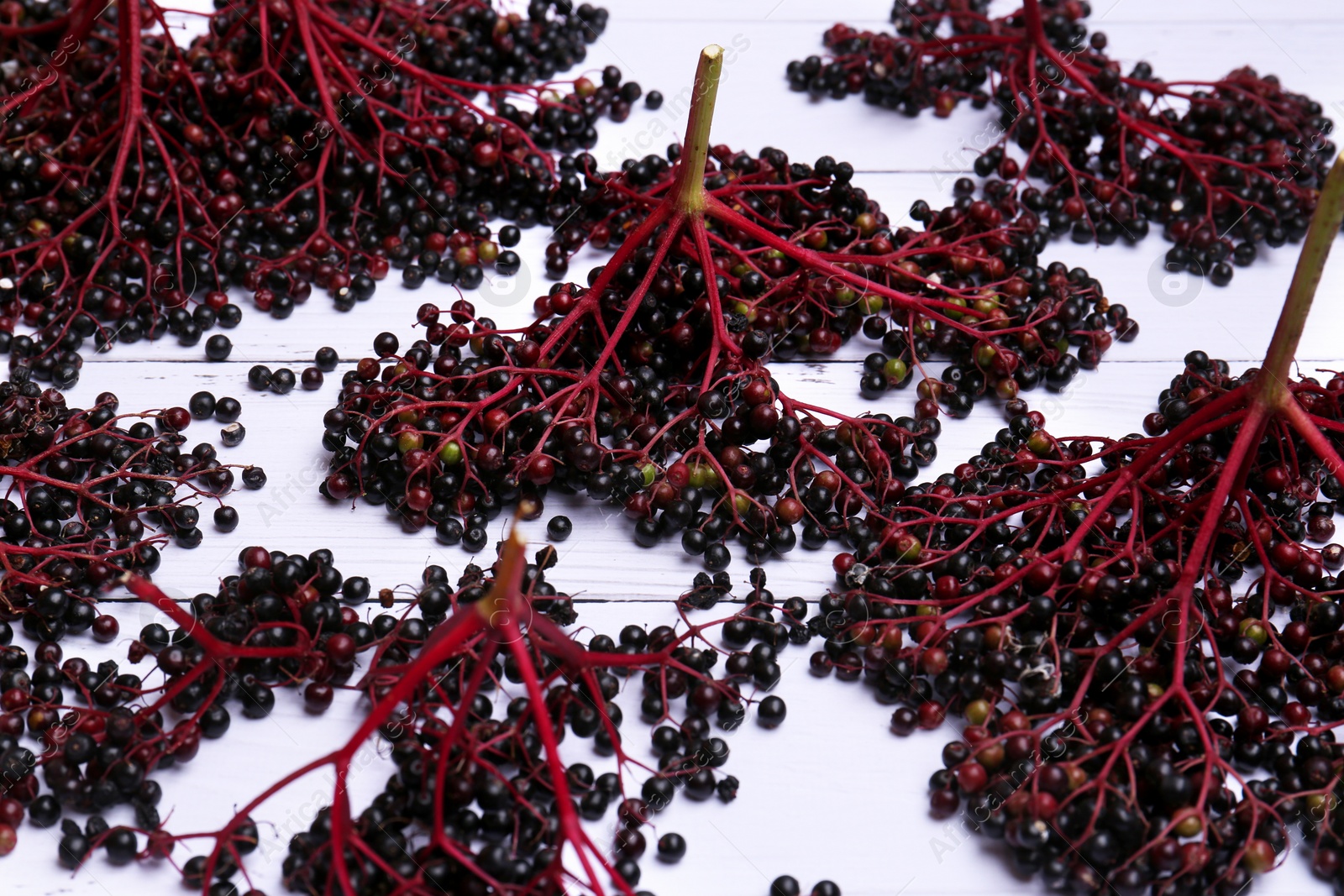 Photo of Tasty elderberries (Sambucus) on white wooden table