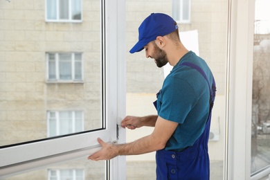 Photo of Construction worker installing plastic window in house