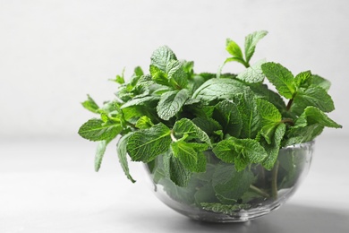 Photo of Glass bowl with fresh green mint on table. Space for text