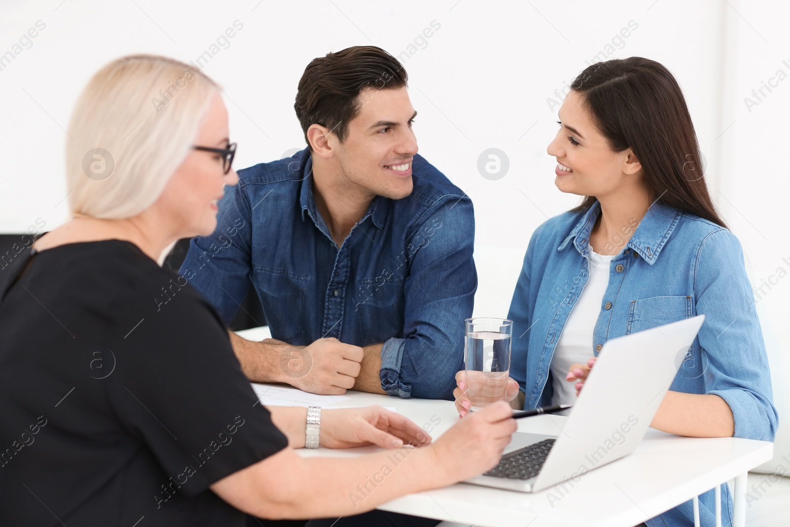 Photo of Young couple discussing pension plan with mature consultant in office