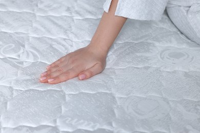 Woman touching soft white mattress, closeup view