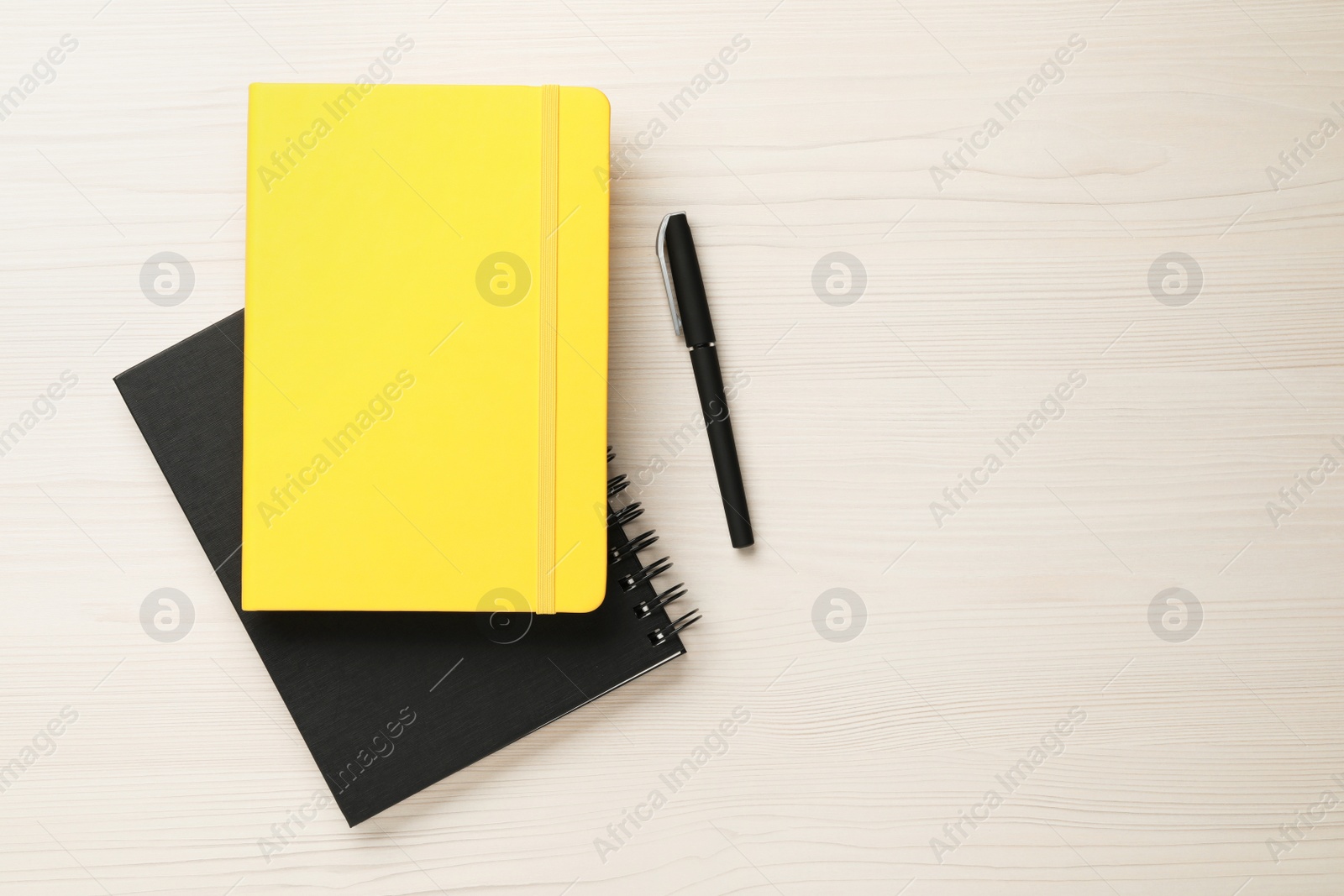 Photo of Notebooks and pen on white wooden table, flat lay Space for text