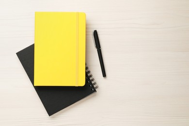 Notebooks and pen on white wooden table, flat lay Space for text