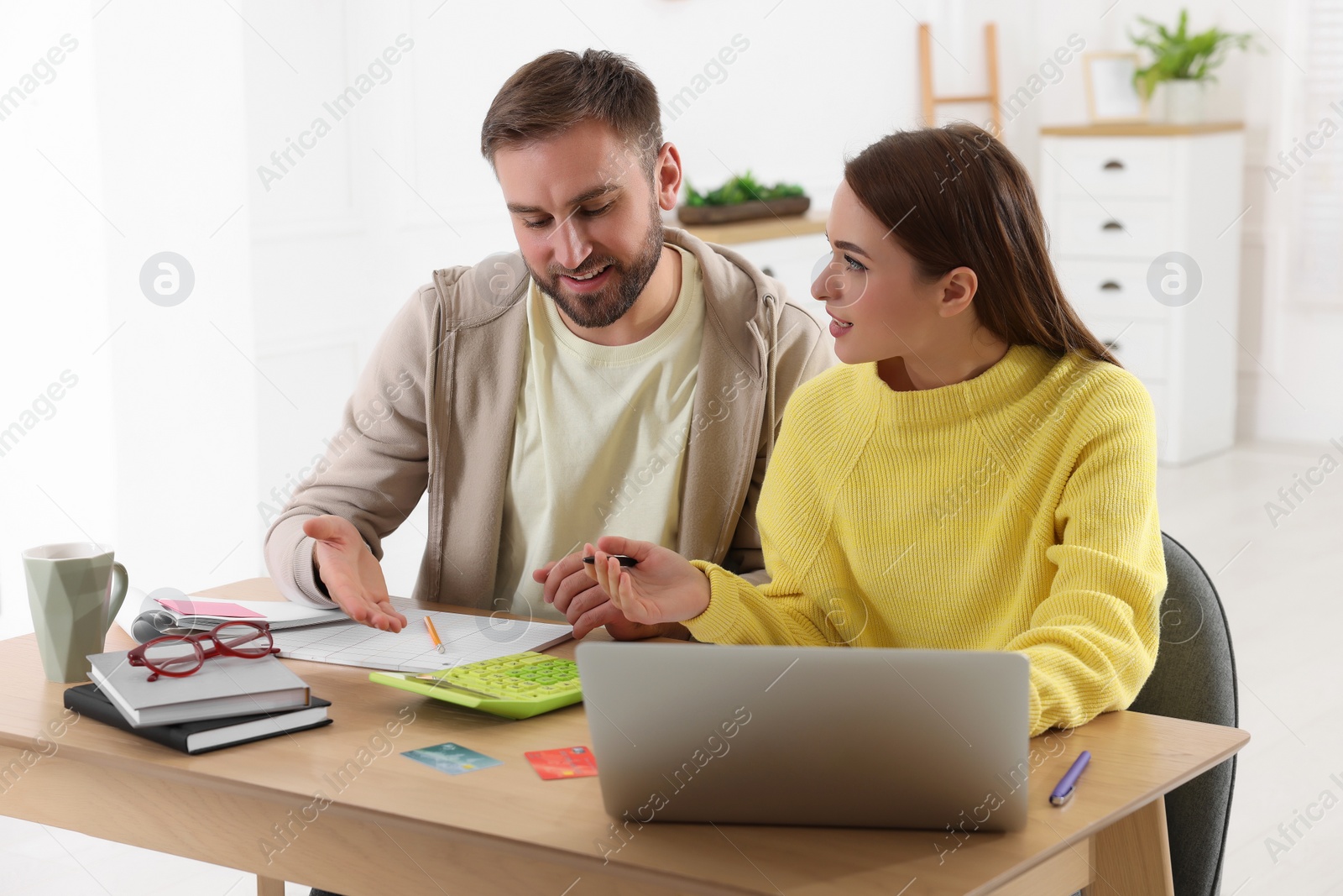 Photo of Young couple discussing family budget at table in living room