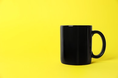 Photo of One black ceramic mug on yellow background. Space for text