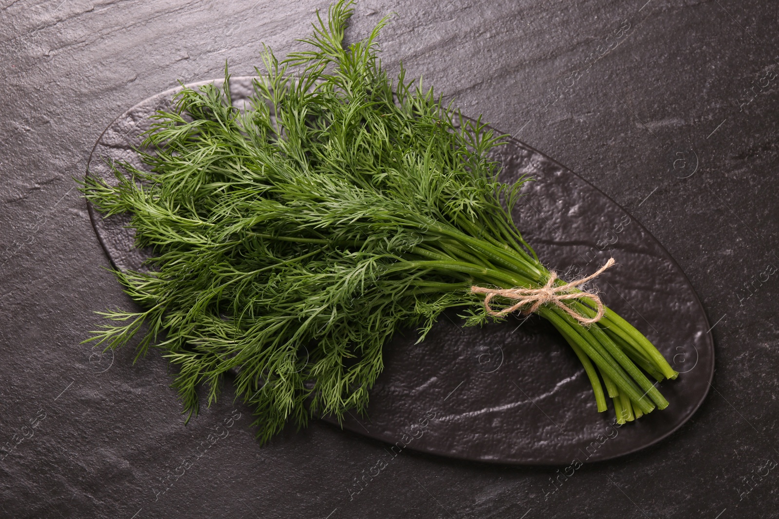 Photo of Bunch of fresh dill on dark textured table, above view