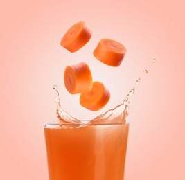 Image of Splashing freshly made carrot juice on pink background. Cut carrot falling into glass