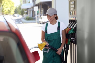 Photo of Young worker refueling car at modern gas station