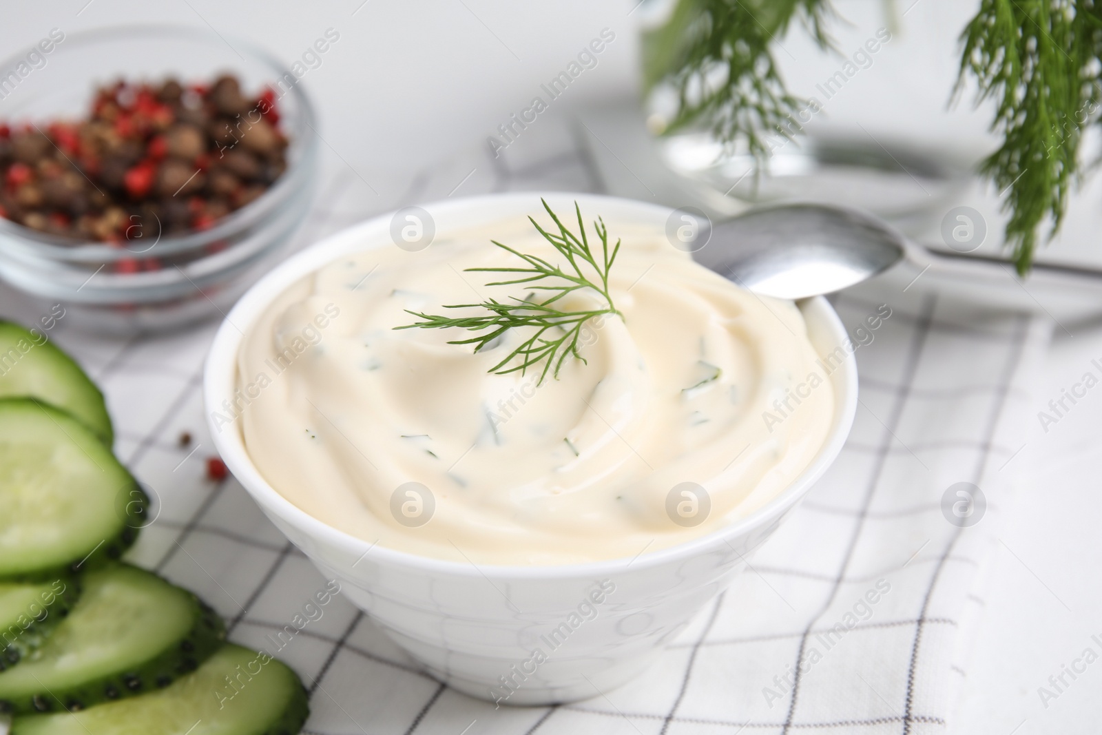 Photo of Tasty creamy dill sauce in bowl on white kitchen towel, closeup