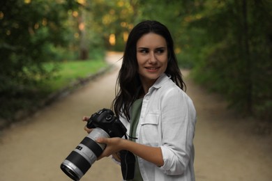 Beautiful woman with camera spending time in nature reserve