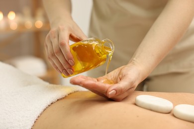 Aromatherapy. Woman receiving back massage with oil in spa salon, closeup