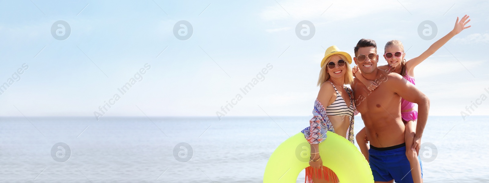 Image of Happy family with inflatable ring at beach on sunny day, space for text. Banner design