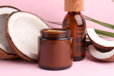 Different hand care cosmetic products and coconut on pink background, closeup