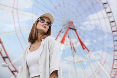 Photo of Beautiful young woman near Ferris wheel outdoors