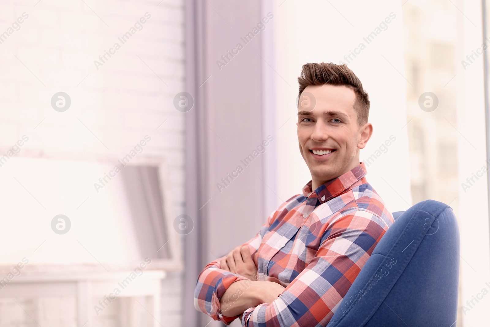 Photo of Young man sitting in armchair at home