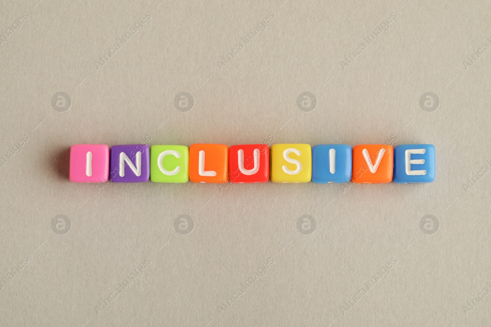 Photo of Colorful cubes with word Inclusive on beige background