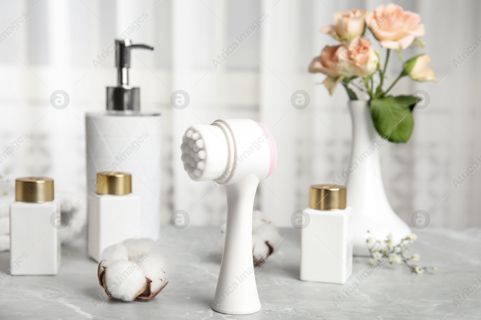 Photo of Modern face cleansing brush on light grey marble table. Cosmetic accessory