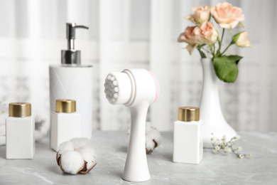 Photo of Modern face cleansing brush on light grey marble table. Cosmetic accessory
