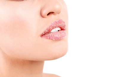 Young woman with sugar scrub on lips against white background, closeup