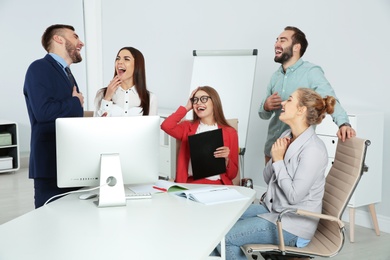 Photo of Group of office employees laughing in conference room