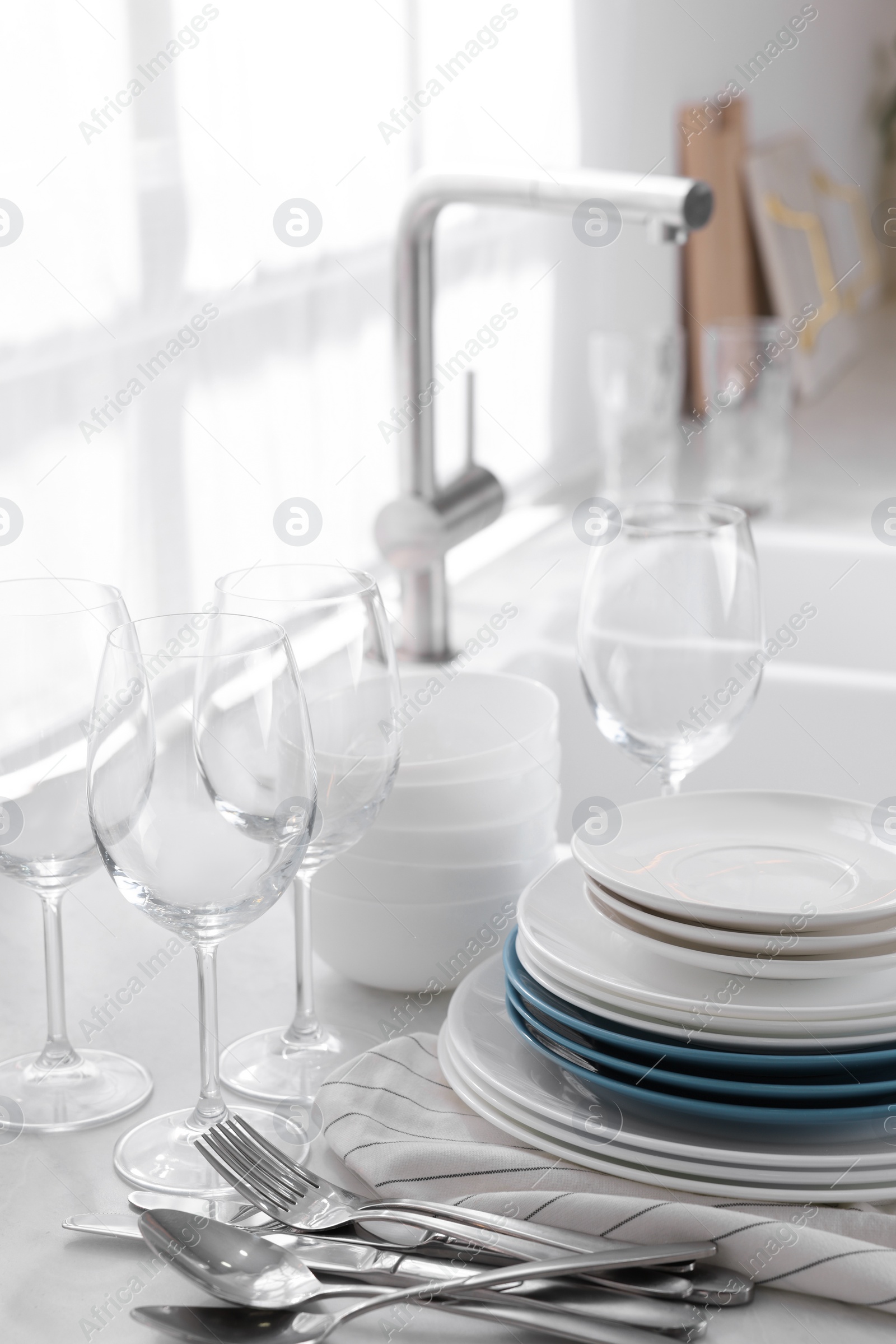 Photo of Different clean dishware, cutlery and glasses on countertop in kitchen