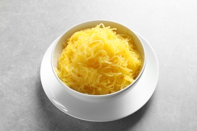 Bowl with cooked spaghetti squash on grey background