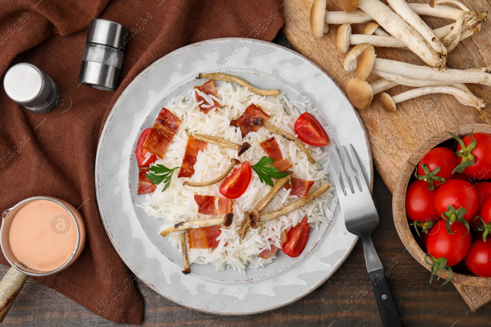 Photo of Delicious rice with bacon, mushrooms and tomatoes served on table, flat lay