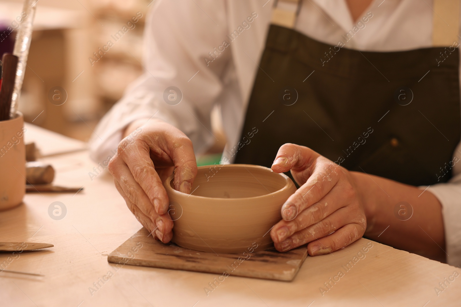 Photo of Pottery crafting. Woman sculpting with clay at table, closeup