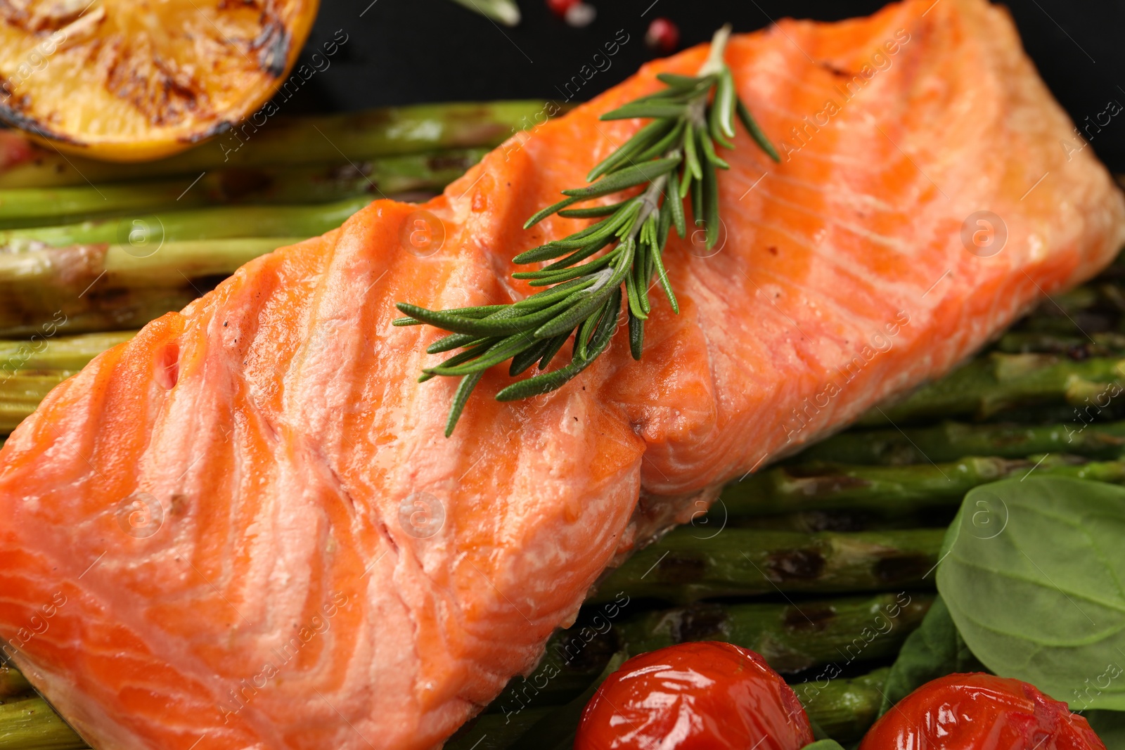 Photo of Tasty grilled salmon with tomatoes, asparagus and rosemary on plate, closeup