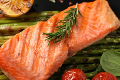 Photo of Tasty grilled salmon with tomatoes, asparagus and rosemary on plate, closeup