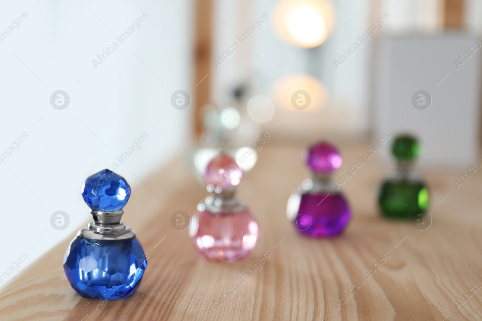 Photo of Different perfume bottles on wooden shelf indoors. Space for text