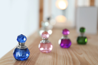 Photo of Different perfume bottles on wooden shelf indoors. Space for text