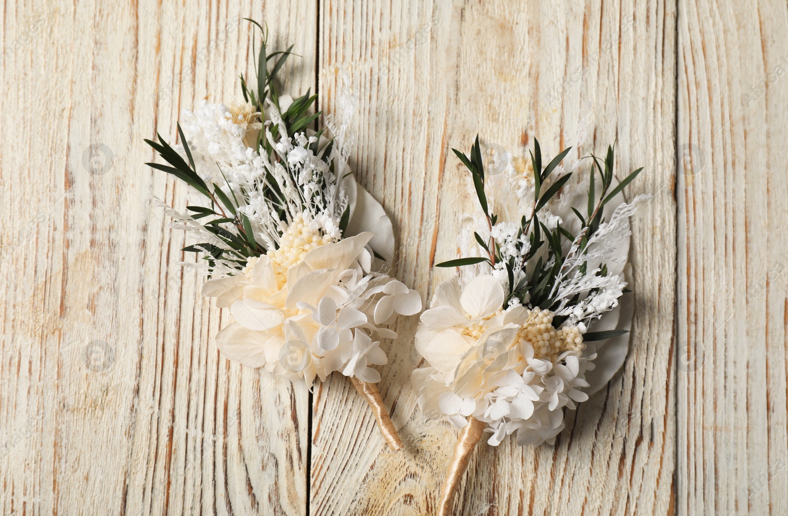 Photo of Stylish boutonnieres on light wooden table, top view